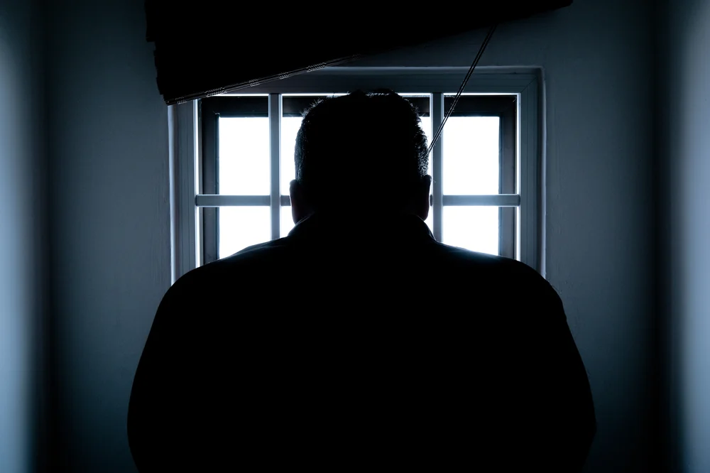 A silhouette of someone sitting in a prison cell